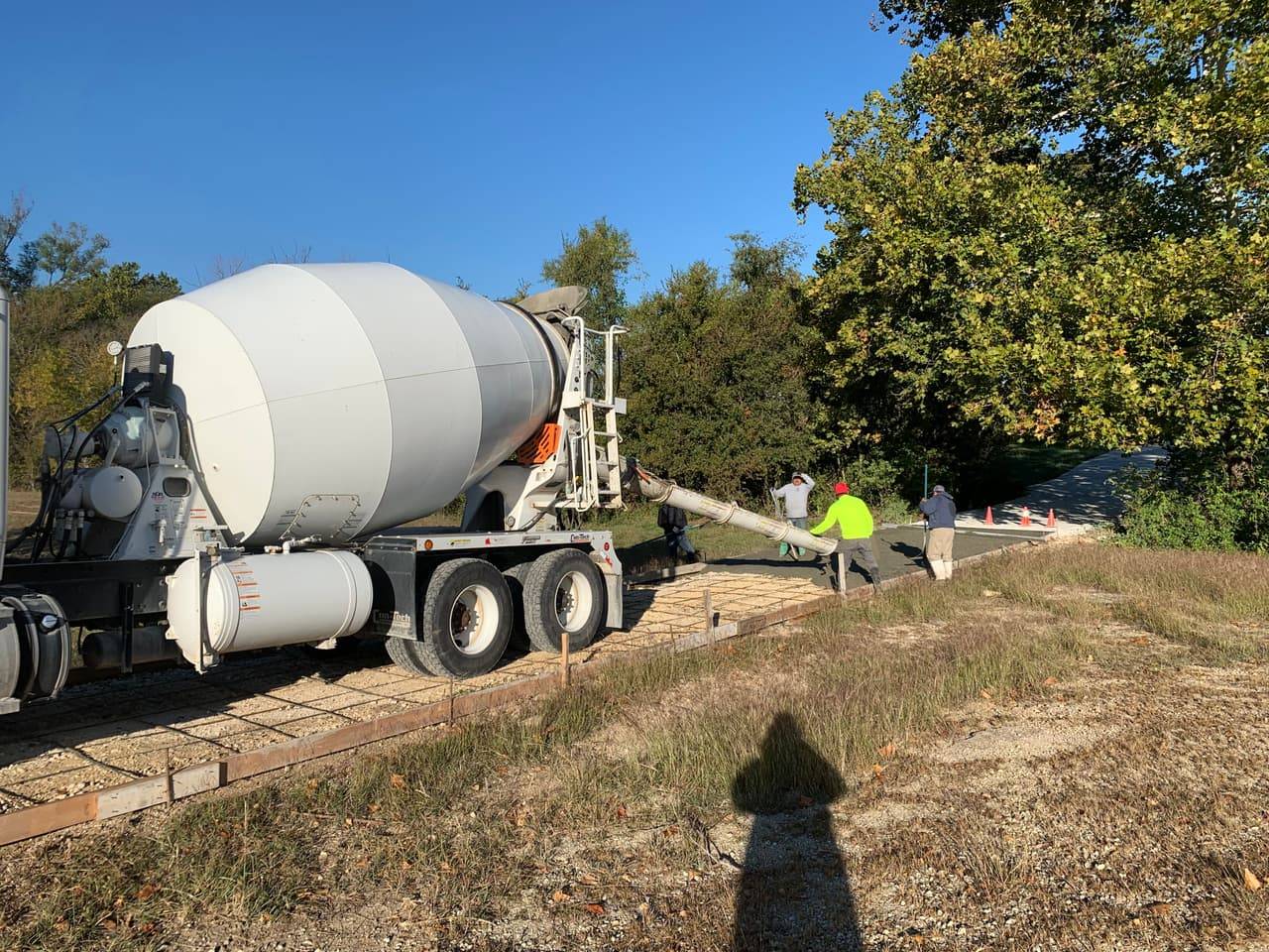 Concrete mixer truck and pump crew pouring a roadside driveway approach